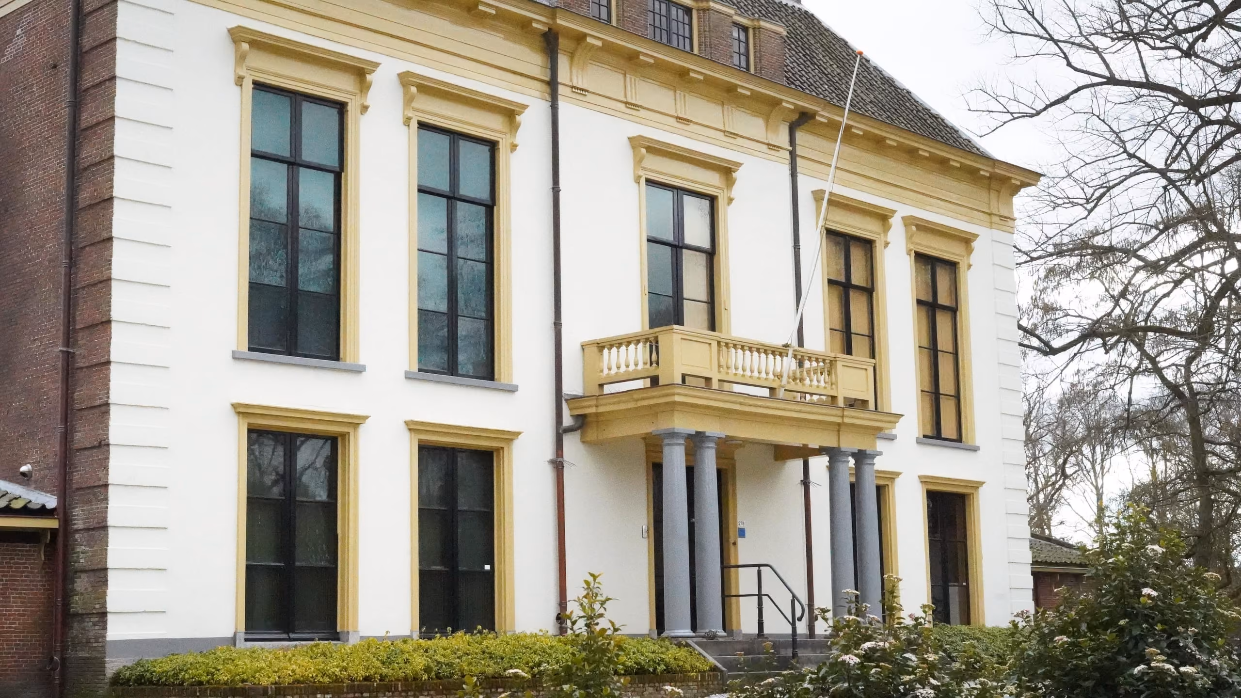 Detail van de wit-gele voorgevel met balkon van Nijenburg